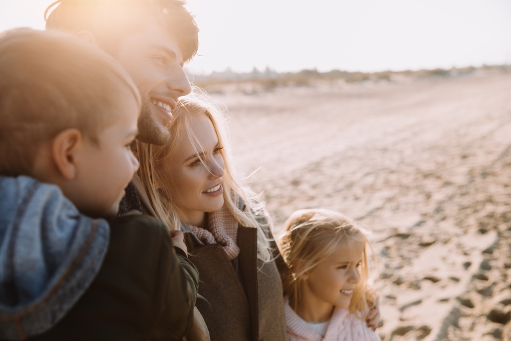 Life insurance concept image - portrait of a happy family near the seashore